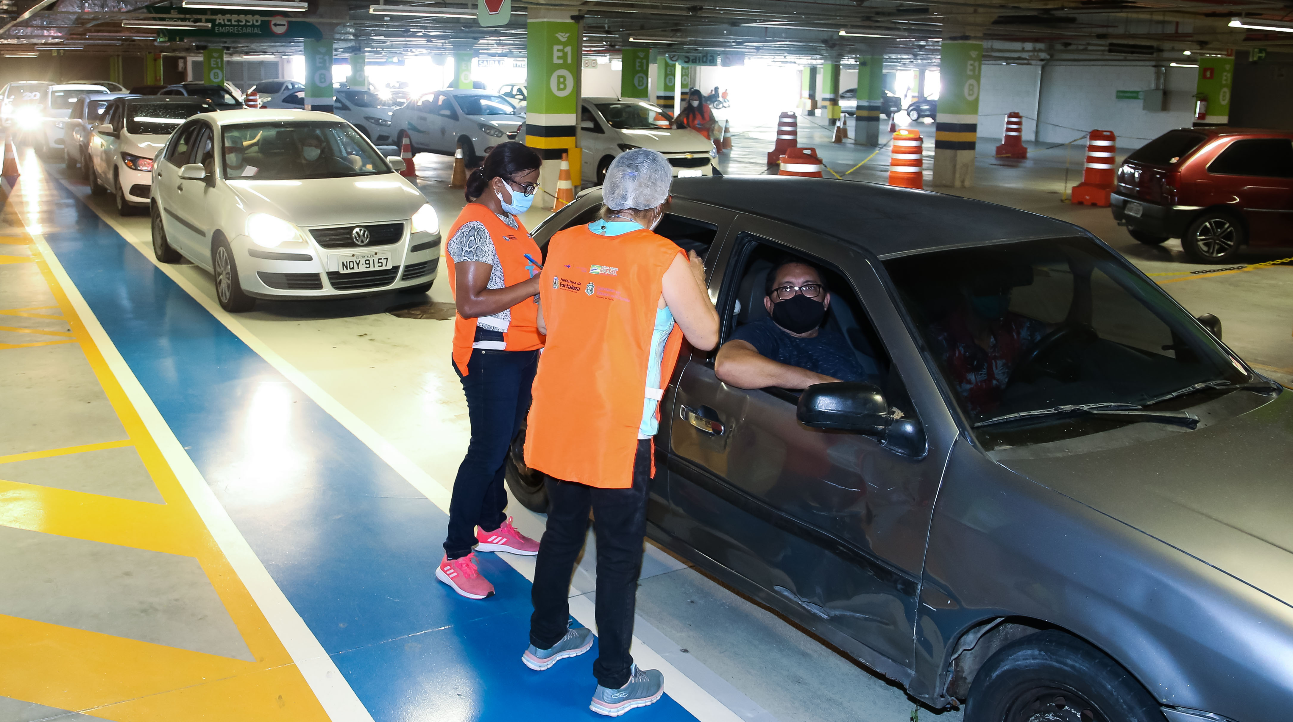 enfermeiro vacina uma senhora dentro de um carro